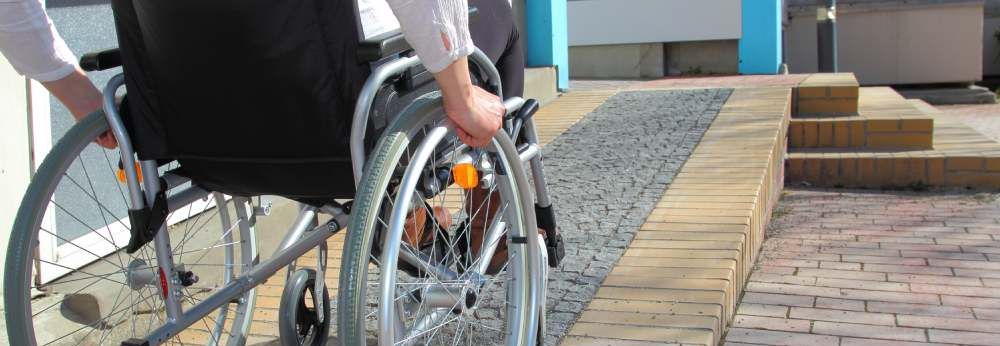 Person im Rollstuhl auf Rollstuhlrampe.